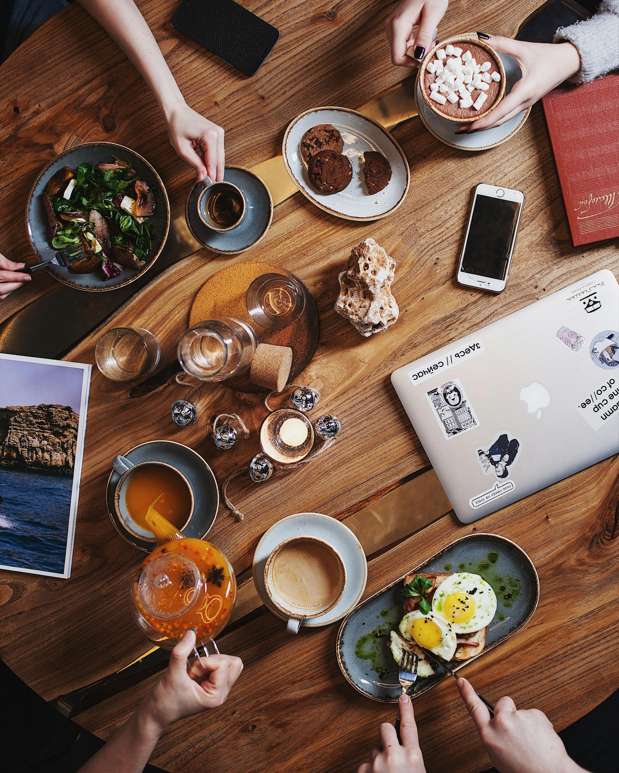 A group enjoying a diverse brunch spread with coffee on a rustic wooden table. Perfect for food and lifestyle themes.